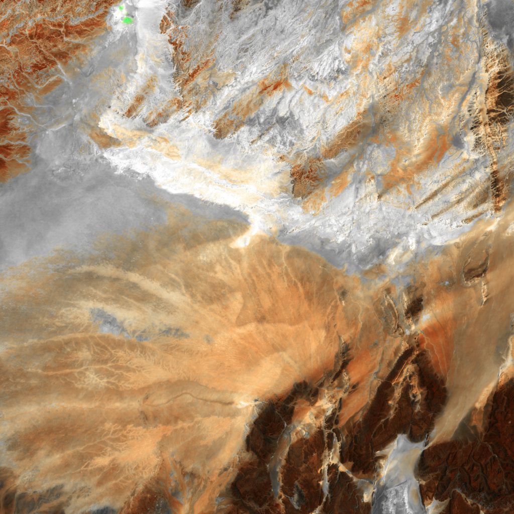 This abstract in browns and grays from central Algeria shows that some parts of Africa's Sahara Desert contain much more than dunes of wind-blown sand. Barren ridges and fragmented mountains (lower right) border a vast expanse of arid plains etched with a complex system of dry streambeds. The streambeds contain water for brief periods following rare, intense rains that often cause flash floods.
